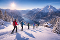 Gruppe von sechs Personen mit Skiern und Wanderstöcken steigt auf schneebedecktem Hang mit Blick auf verschneite Berge und einen See im Tal