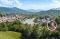 Blick auf eine Stadt mit Fluss, Brücke und bewaldeten Hügeln im Hintergrund bei klarem Himmel